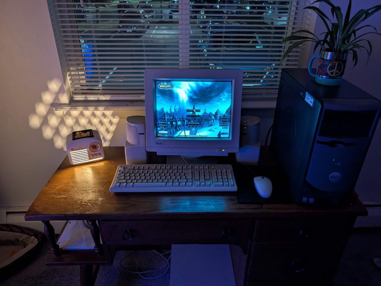 A CRT monitor on a wooden desk, running World of Warcraft, lit by a small radio